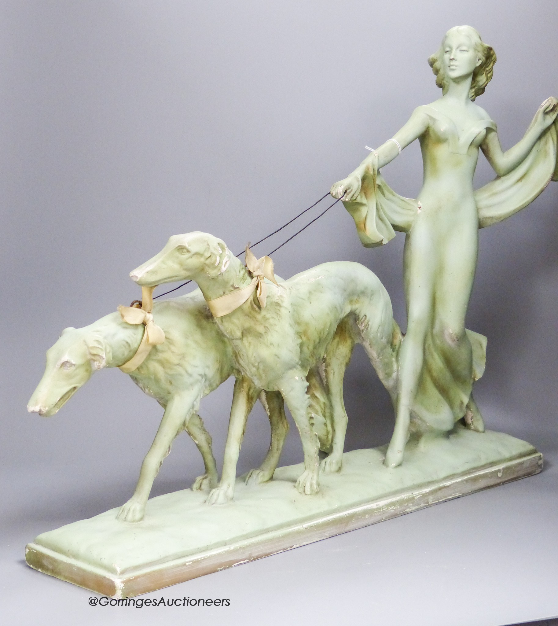 An Art Deco green painted pottery group of a lady and two Borzoi, width 63cm